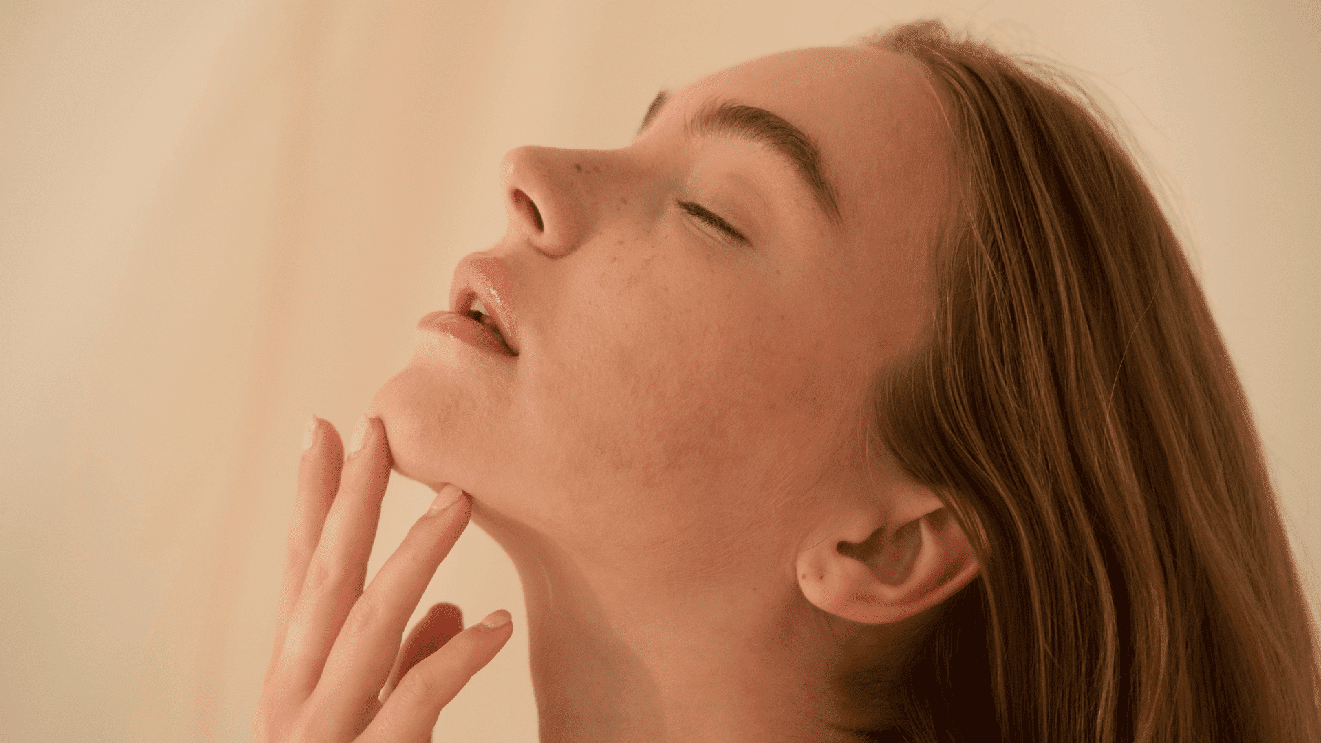 Young woman with closed eyes, relaxing with fingers near her chin.