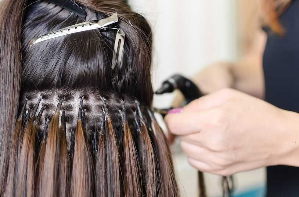 Hair extensions being applied to a woman's head using weaving technique.